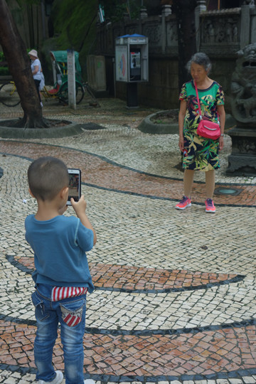 A small boy taking a picture of his grandmother at the old A-Ma Temple